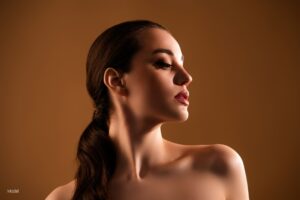 woman with smooth skin looking to the right in front of a brown background